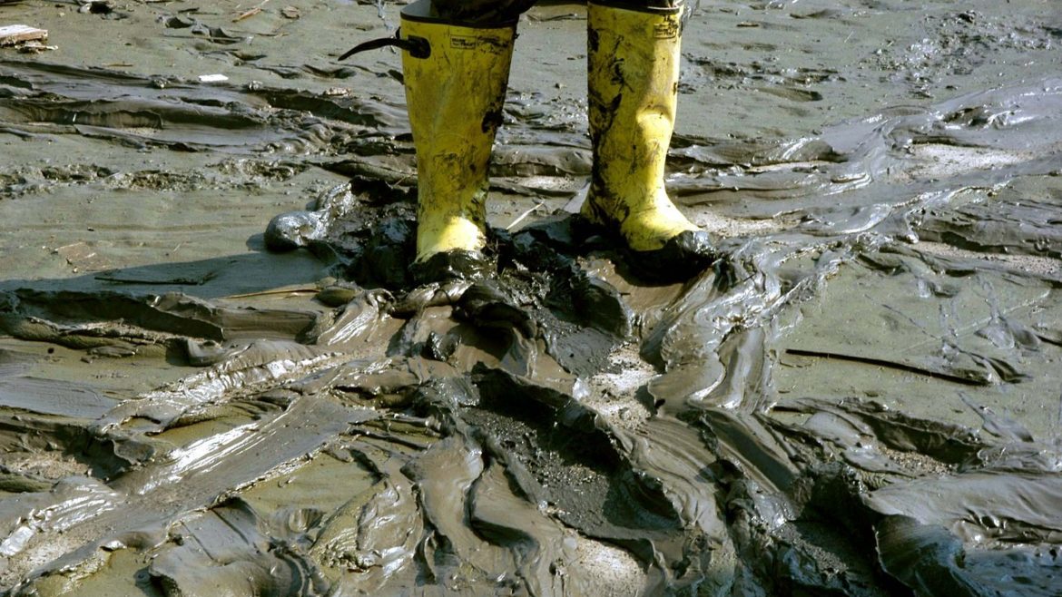 man with rain boots in mud - PayReel