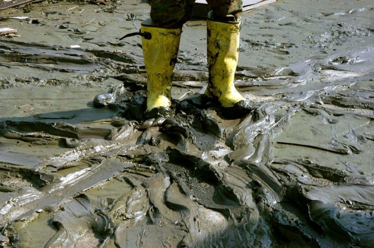 man with rain boots in mud - PayReel