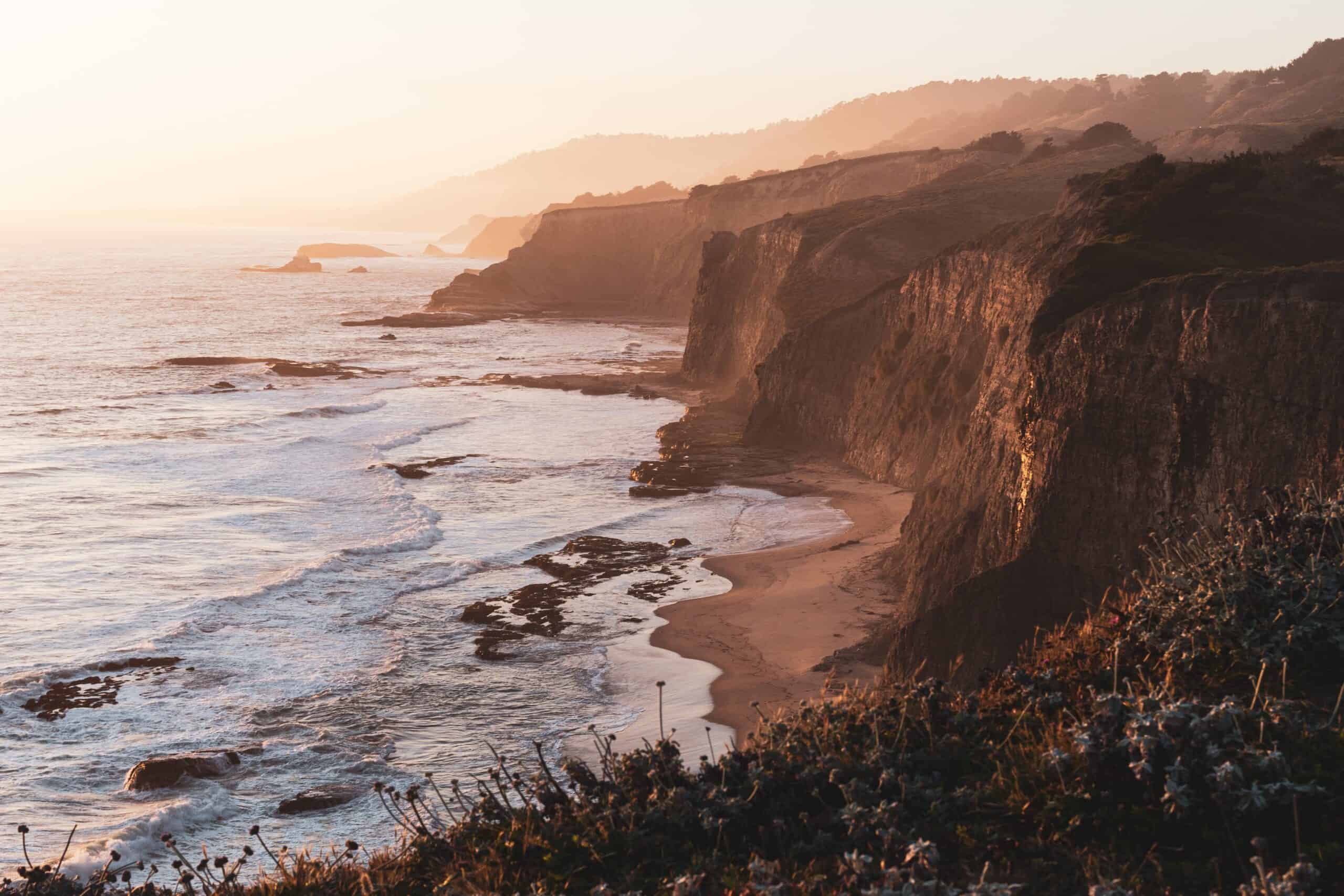 Beautiful image of coast line with steep cliffs and sea washing up to beach